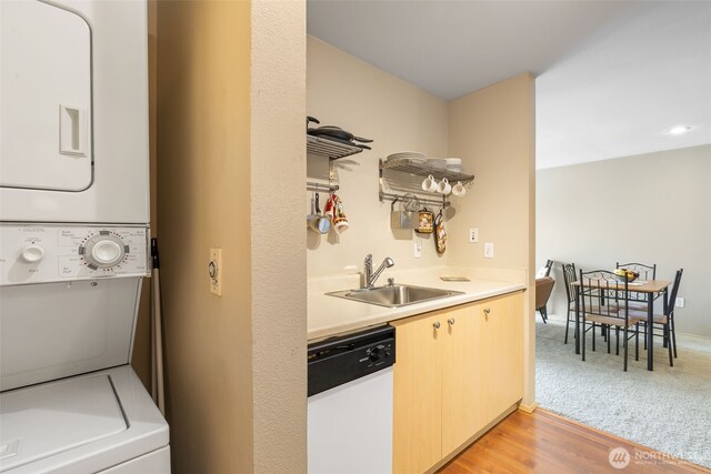 laundry area featuring laundry area, a sink, light wood-style floors, stacked washer and clothes dryer, and indoor bar
