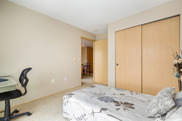 carpeted bedroom with a closet and baseboards