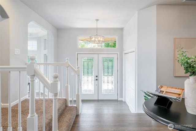 foyer featuring french doors, wood finished floors, a chandelier, and arched walkways