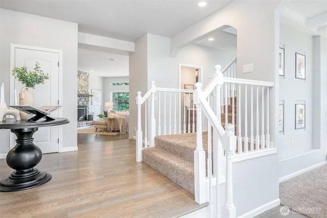 staircase with wood finished floors, recessed lighting, a fireplace, and baseboards