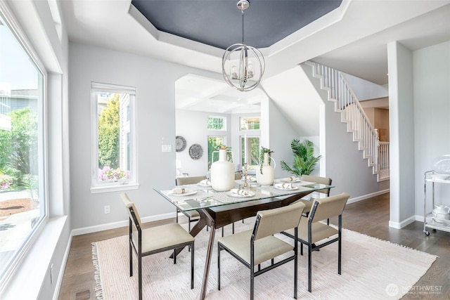 dining space with a chandelier, stairway, dark wood-style flooring, baseboards, and a raised ceiling