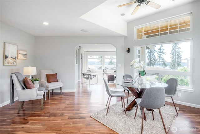 dining space featuring arched walkways, wood finished floors, baseboards, ceiling fan, and recessed lighting