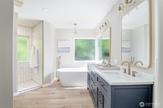 full bathroom featuring a freestanding bath, double vanity, tiled shower, wood finished floors, and baseboards