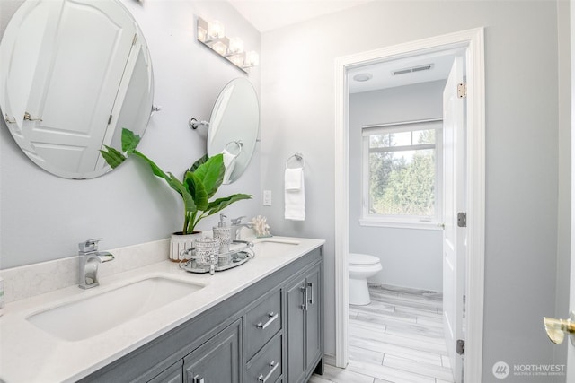 full bathroom with toilet and double vanity
