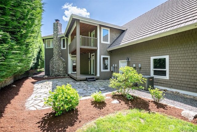 back of house with a balcony, a chimney, a patio, and central AC