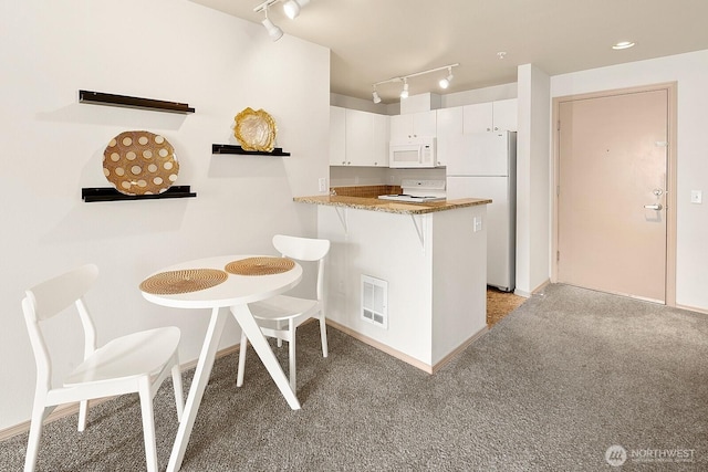 323 Queen Anne Ave N Unit 508, Seattle, WA 98109 - kitchen featuring light colored carpet, visible vents, rail lighting, white appliances, and white cabinetry