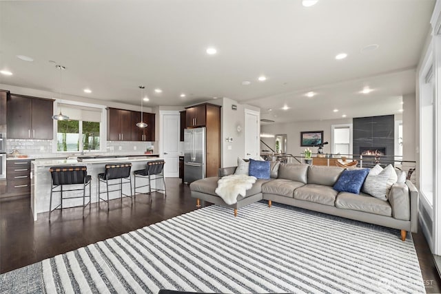 living room with a fireplace, recessed lighting, and dark wood-type flooring