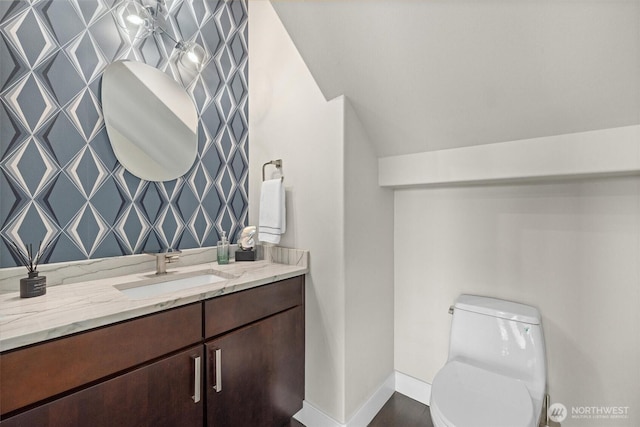 bathroom featuring vaulted ceiling, baseboards, vanity, and toilet