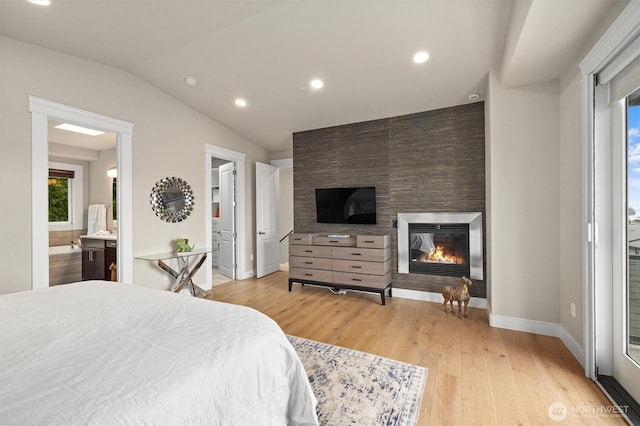 bedroom featuring baseboards, light wood-style flooring, a multi sided fireplace, and vaulted ceiling