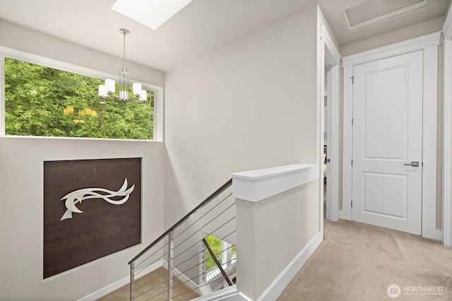 hall with baseboards, carpet flooring, a skylight, and an upstairs landing