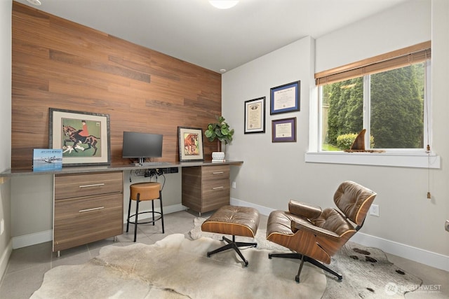 office featuring wooden walls, baseboards, and an accent wall