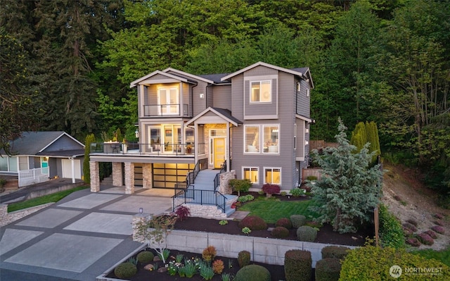 modern home featuring concrete driveway, stairway, a balcony, and a garage