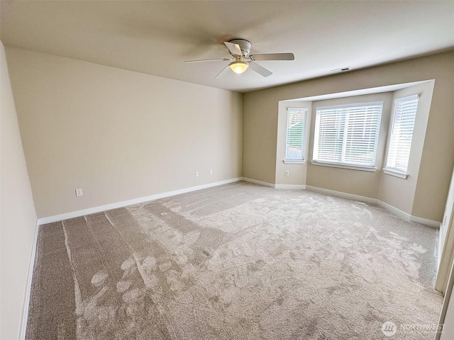 carpeted empty room featuring ceiling fan, visible vents, and baseboards