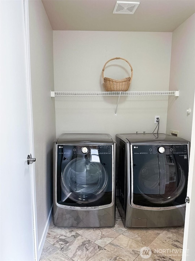 laundry room featuring separate washer and dryer, visible vents, and laundry area