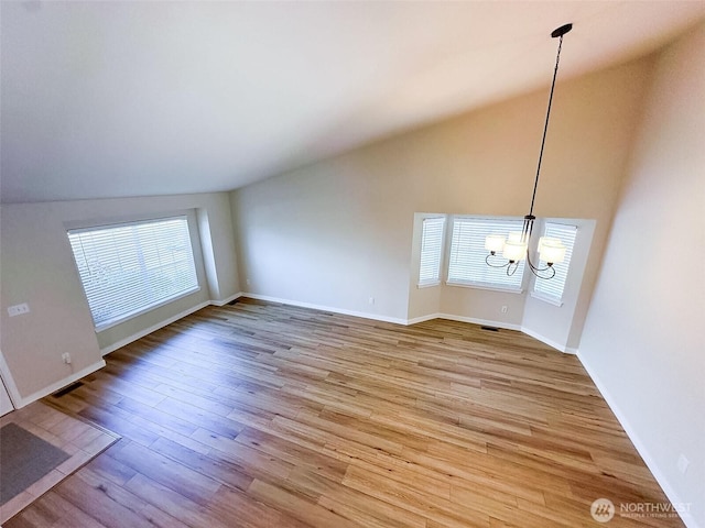 unfurnished living room featuring light wood finished floors, a notable chandelier, visible vents, vaulted ceiling, and baseboards