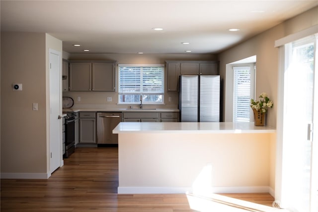 kitchen with a sink, light countertops, gray cabinetry, appliances with stainless steel finishes, and wood finished floors