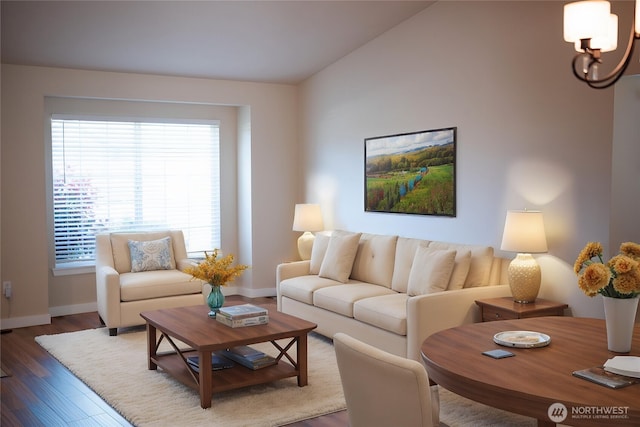 living area featuring lofted ceiling, an inviting chandelier, wood finished floors, and baseboards