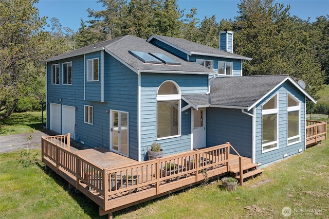 rear view of house with a chimney, a deck, and roof with shingles