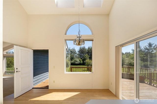 entryway featuring a chandelier, a towering ceiling, and wood finished floors