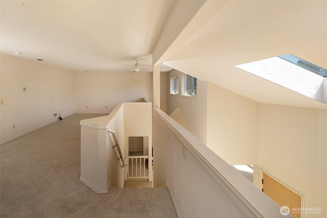 hall with carpet flooring and an upstairs landing