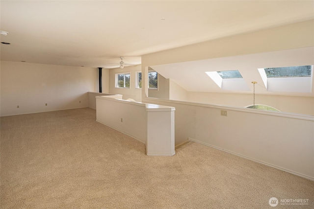 bonus room with light colored carpet, baseboards, and a skylight