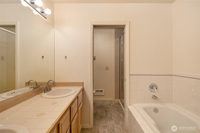 full bathroom featuring a stall shower, a garden tub, double vanity, and a sink