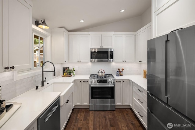 kitchen with backsplash, white cabinets, appliances with stainless steel finishes, and a sink