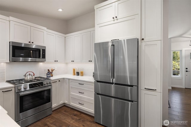 kitchen with light countertops, appliances with stainless steel finishes, decorative backsplash, and dark wood-style floors