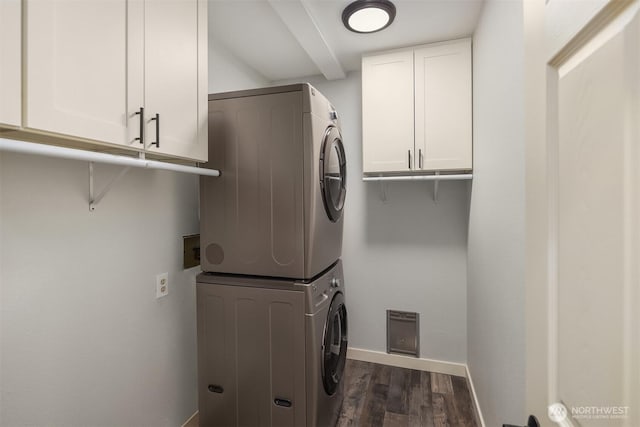 washroom featuring baseboards, stacked washer and clothes dryer, dark wood finished floors, and cabinet space