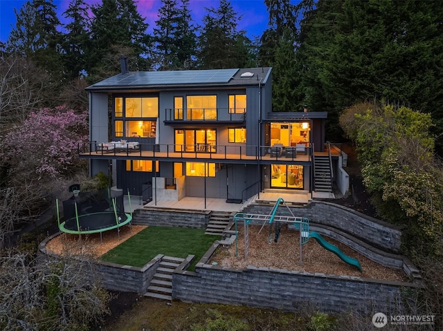 5340 W Mercer Way, Mercer Island, WA 98040 - rear view of house with a trampoline, stairs, solar panels, a patio, and board and batten siding