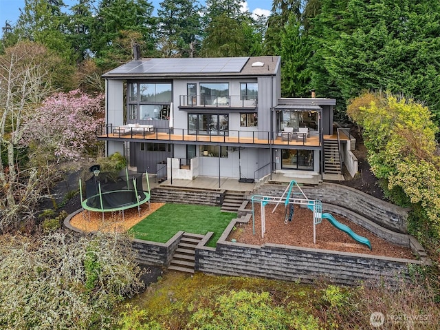 5340 W Mercer Way, Mercer Island, WA 98040 - rear view of property featuring a trampoline, stairway, roof mounted solar panels, a playground, and a patio area