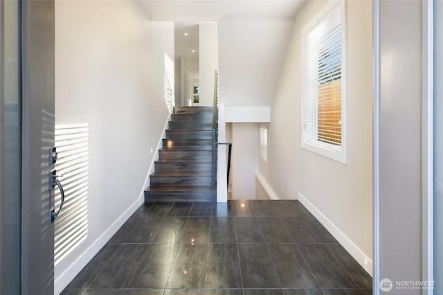 stairway with baseboards, plenty of natural light, and tile patterned flooring