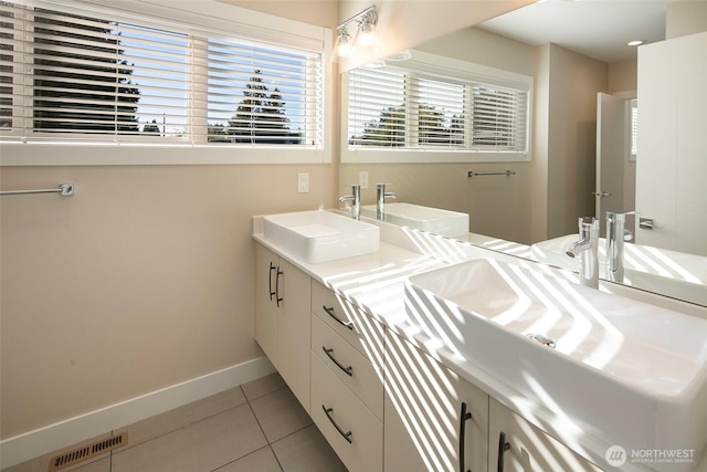 full bath featuring a sink, double vanity, tile patterned floors, baseboards, and visible vents