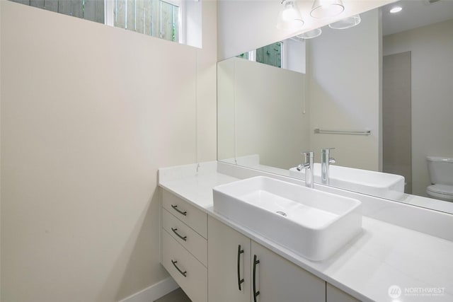 bathroom featuring vanity, baseboards, and toilet
