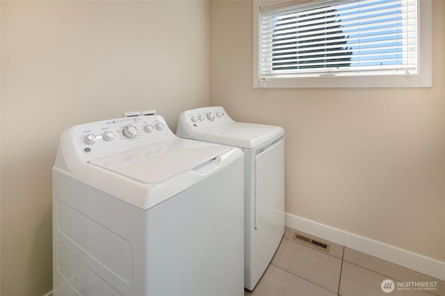 clothes washing area featuring laundry area, visible vents, baseboards, tile patterned floors, and separate washer and dryer