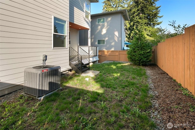 view of yard with central AC unit and a fenced backyard