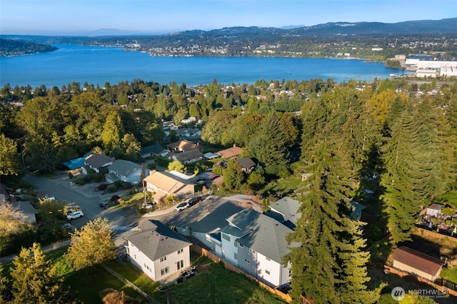 birds eye view of property featuring a water view and a wooded view