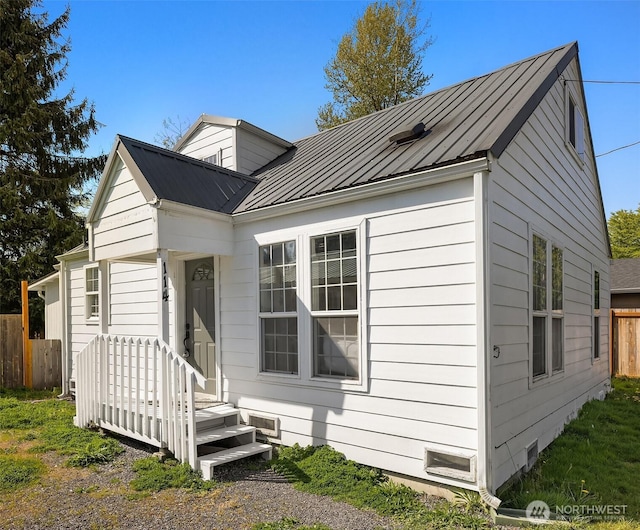 view of front facade with a standing seam roof, fence, and metal roof