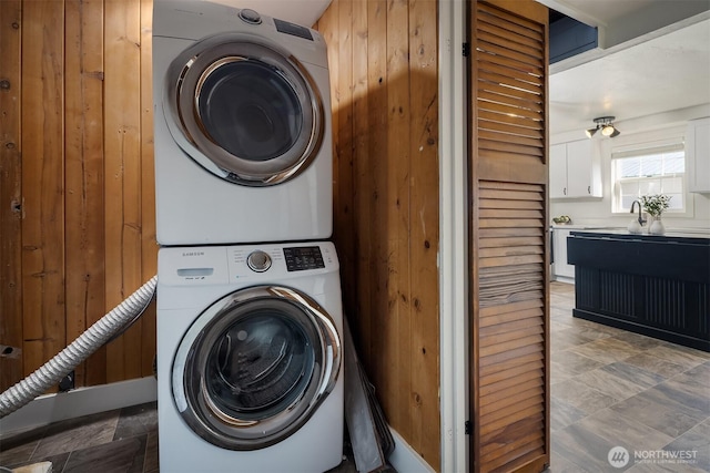 laundry area featuring stacked washer and clothes dryer, stone finish floor, and laundry area