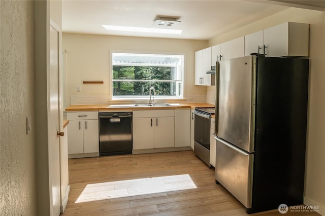 kitchen featuring a sink, butcher block counters, light wood-style flooring, appliances with stainless steel finishes, and ventilation hood