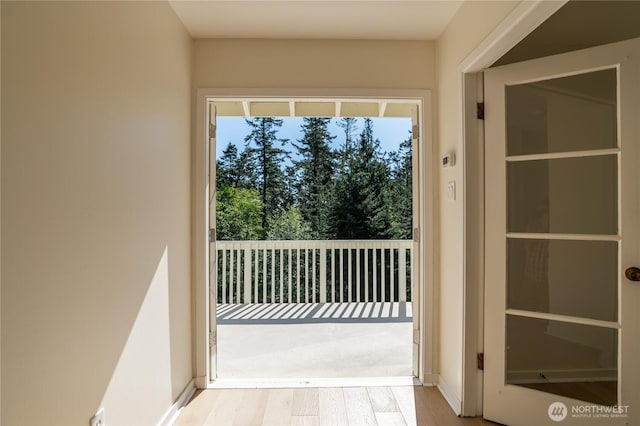 doorway featuring baseboards and wood finished floors