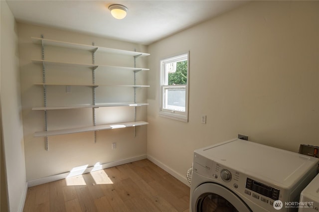clothes washing area featuring light wood-style flooring, baseboards, laundry area, and washer / dryer