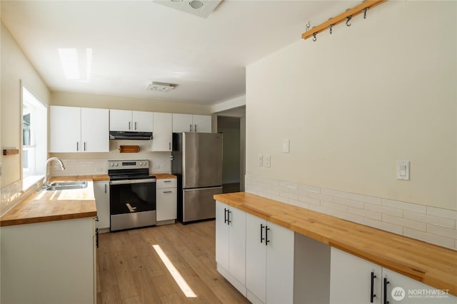 kitchen with wood counters, backsplash, stainless steel appliances, and a sink