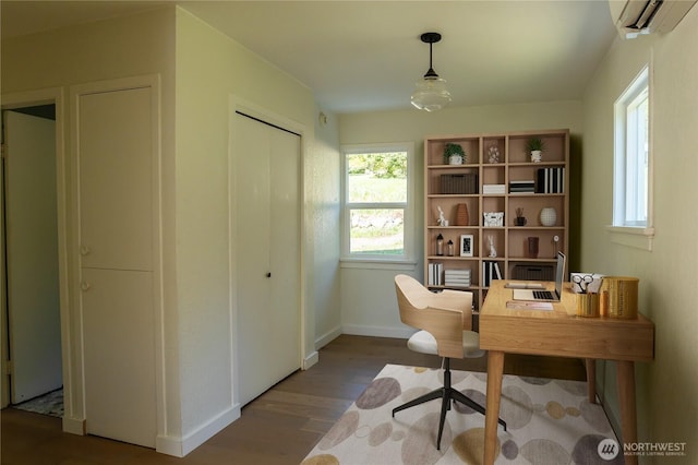 office space featuring a wall mounted AC, plenty of natural light, baseboards, and wood finished floors