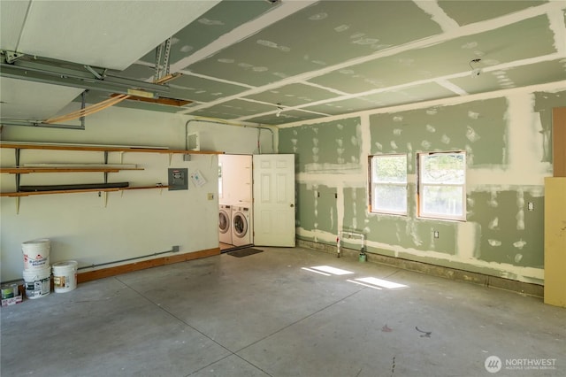 garage with electric panel and washing machine and clothes dryer