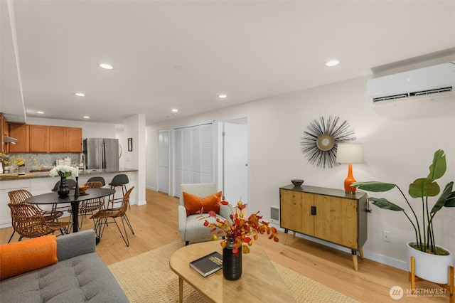 living area featuring baseboards, recessed lighting, light wood-style floors, and a wall mounted air conditioner