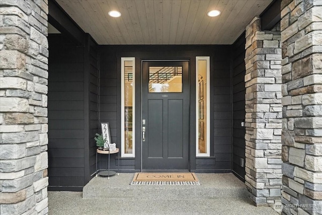 view of exterior entry featuring stone siding and covered porch