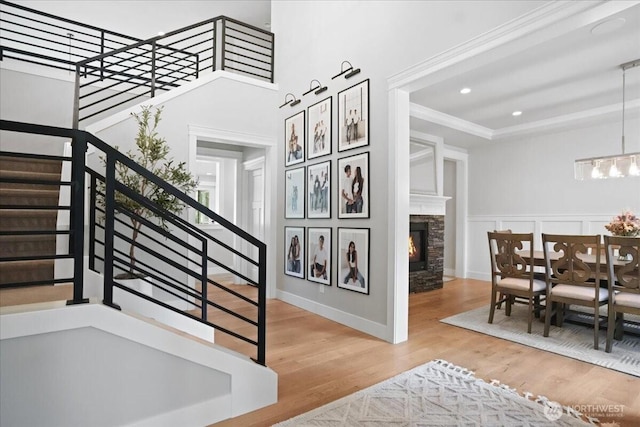 stairs featuring crown molding, wood finished floors, an inviting chandelier, a fireplace, and recessed lighting