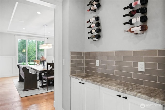 kitchen with decorative backsplash, light stone counters, light wood-style floors, and white cabinets