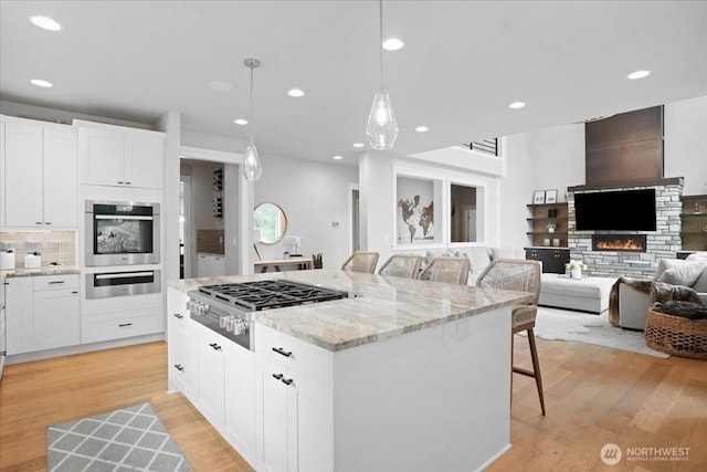 kitchen with light stone countertops, a kitchen island, appliances with stainless steel finishes, a breakfast bar area, and white cabinetry
